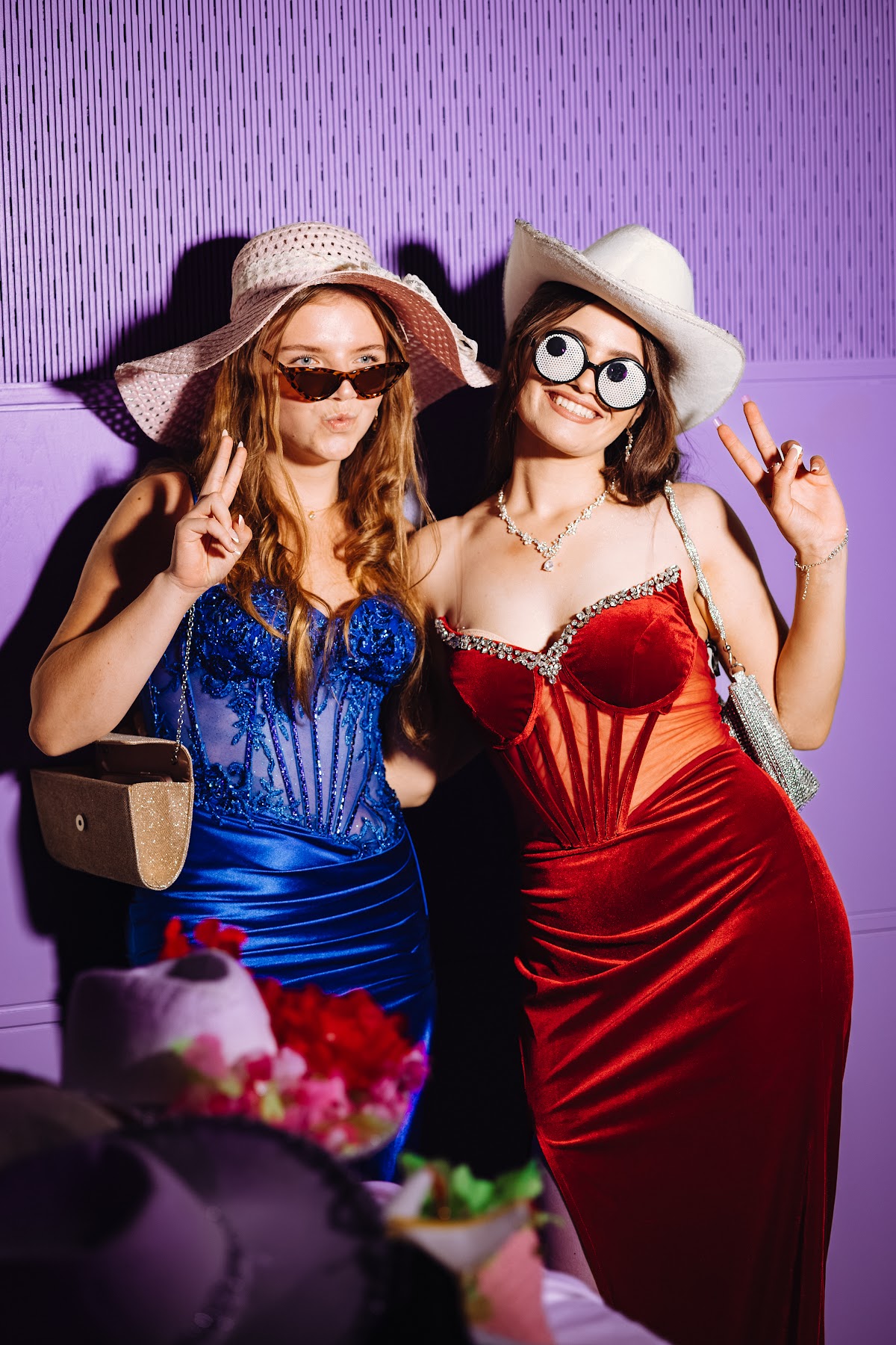 Two friends posing with playful photobooth props